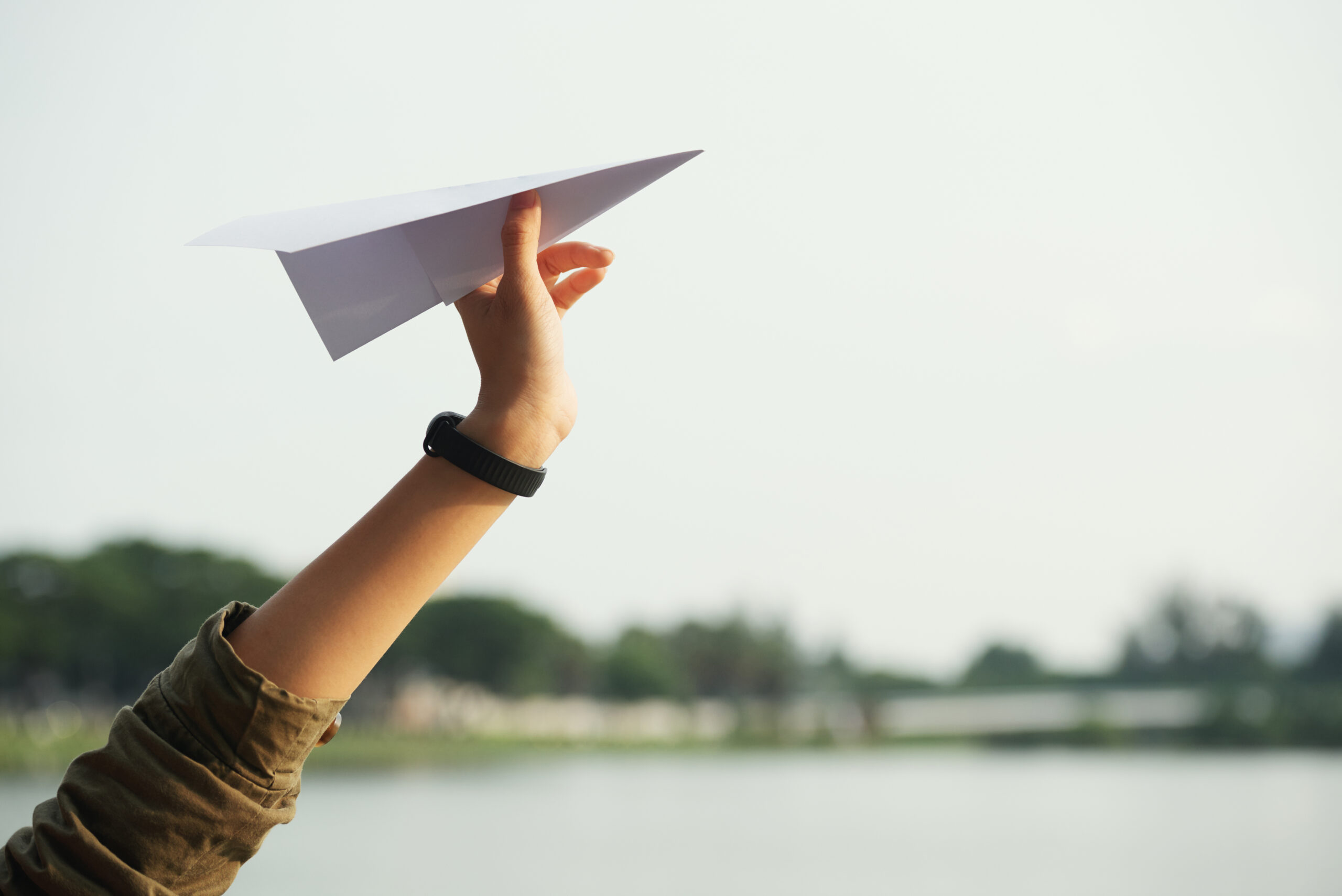 closeup-teenage-hand-throwing-paper-plane